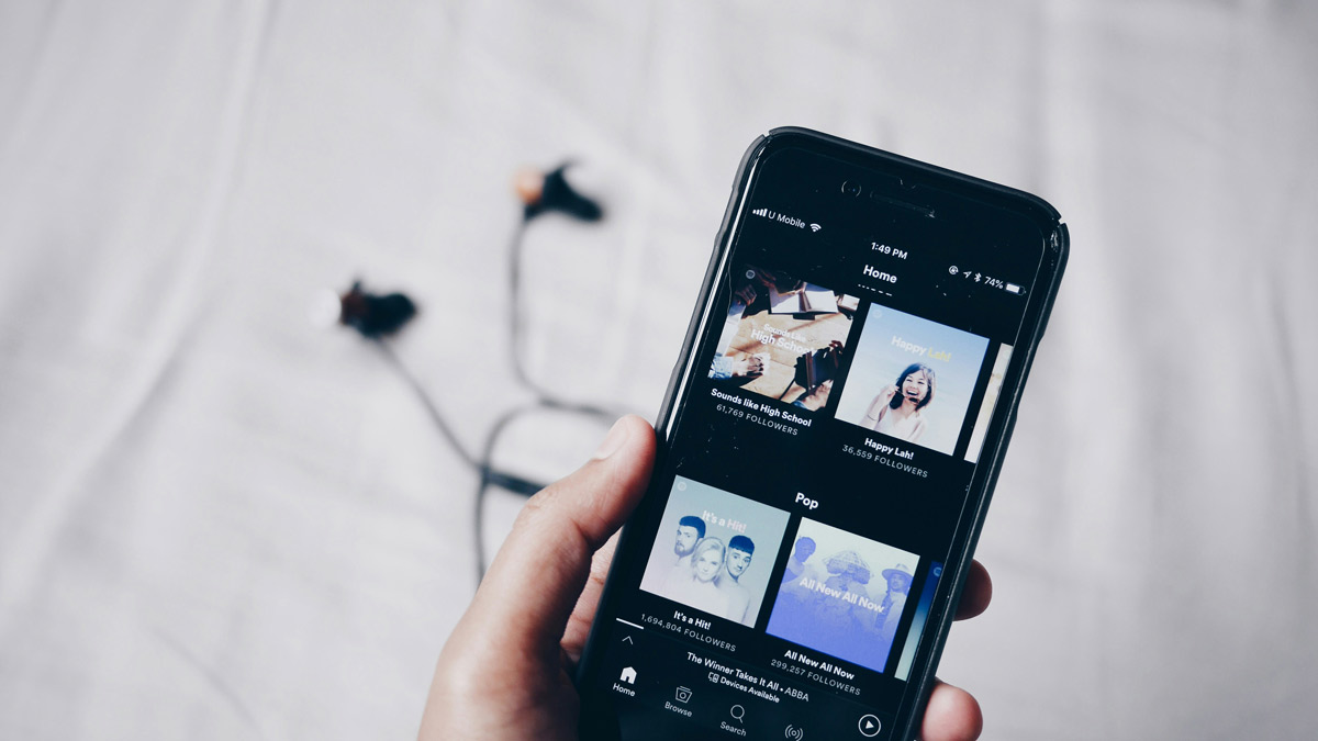 Hand holding a smartphone displaying the Spotify app, representing how artists can boost Spotify streams, grow Spotify followers, and use Spotify algorithm tips for organic music promotion. Highlights how listener engagement helps with how to get on Spotify playlists.